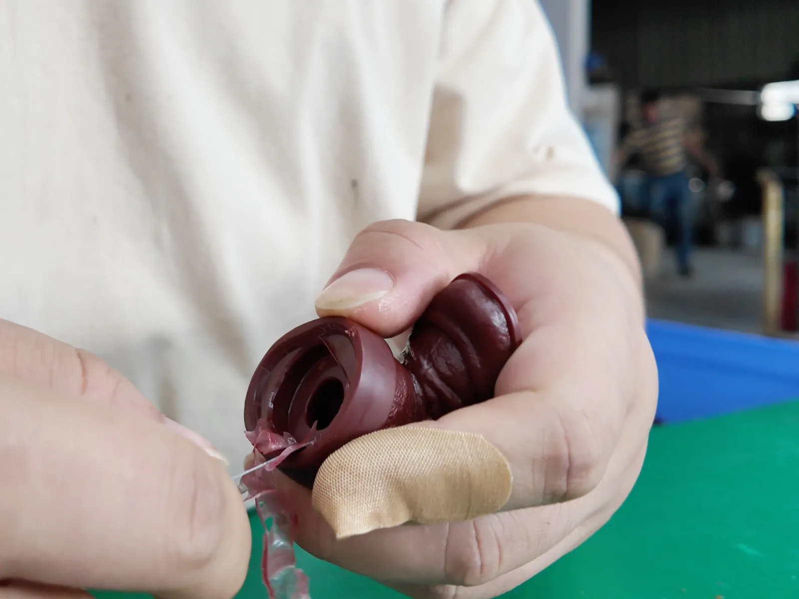 The operator is manually removing excess edges and corners from the vinyl figure parts.