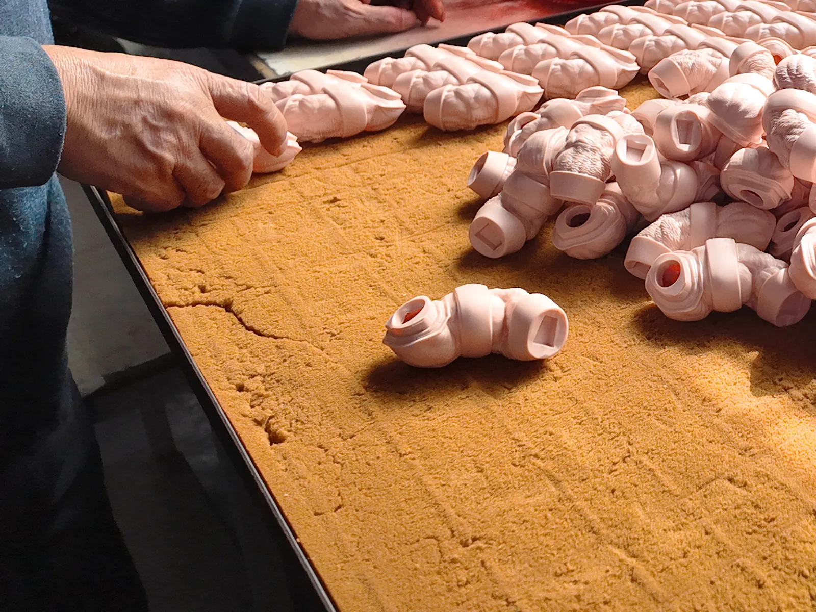 The operators arrange the vinyl toy parts, preparing to put them into the oven all at once.