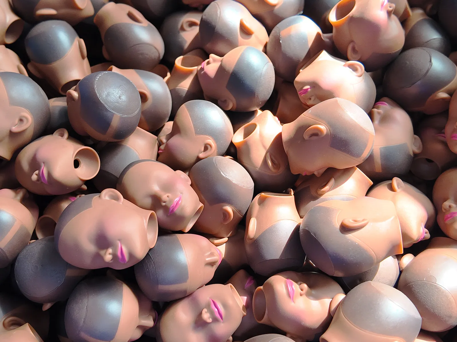 A large number of vinyl toy heads without painted eyes.