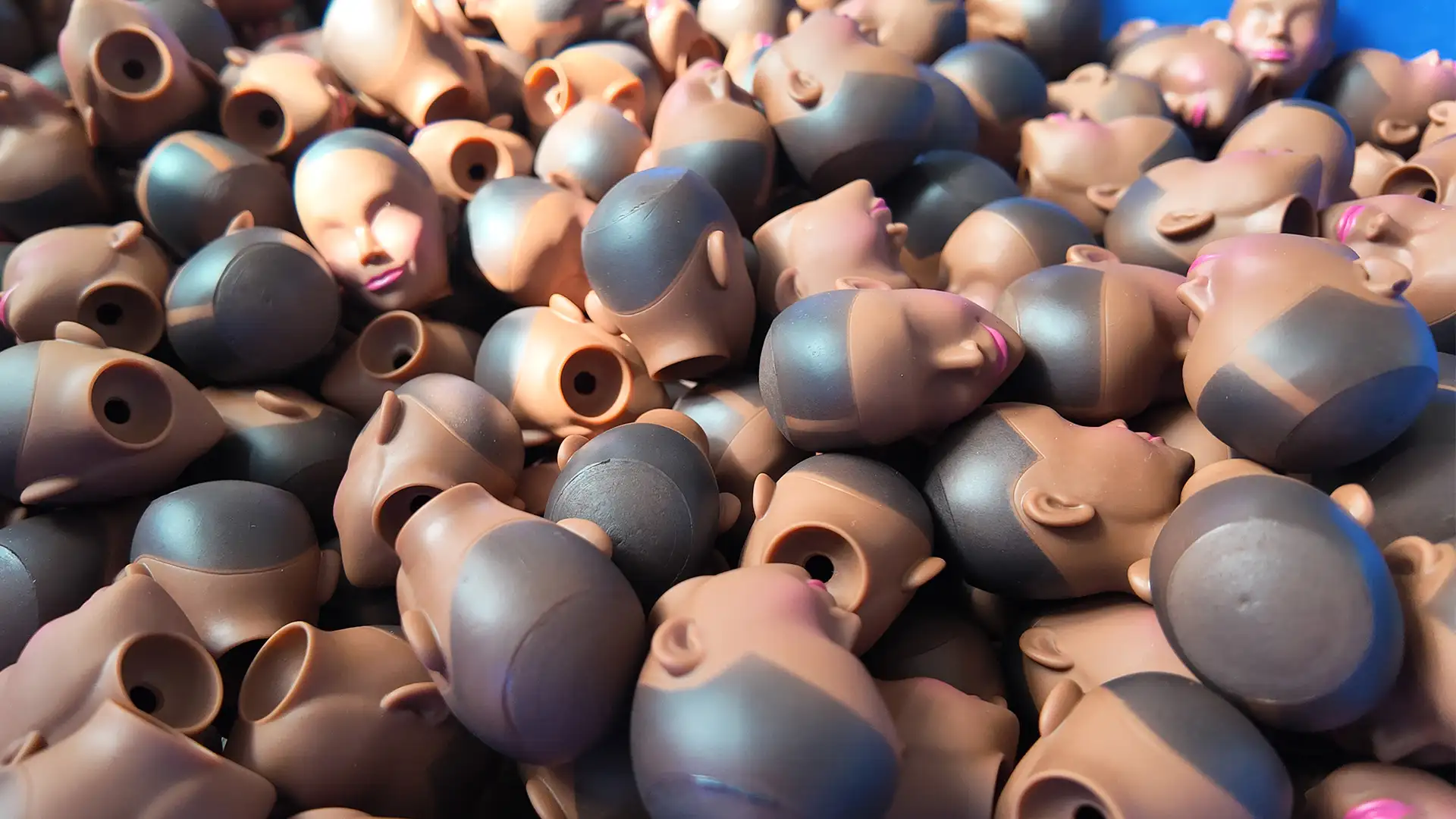 A large number of already painted vinyl doll heads, which will undergo the rooting process next